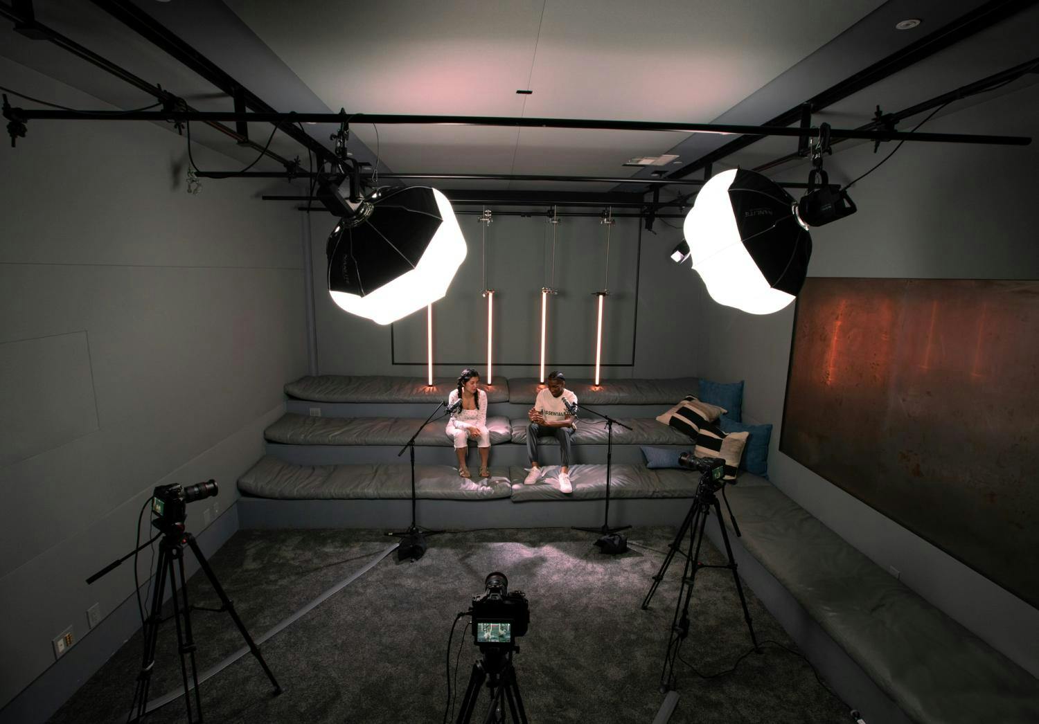 A top-down view of a professional studio setup, with a pair of interviewees sitting on a couch under studio lighting.